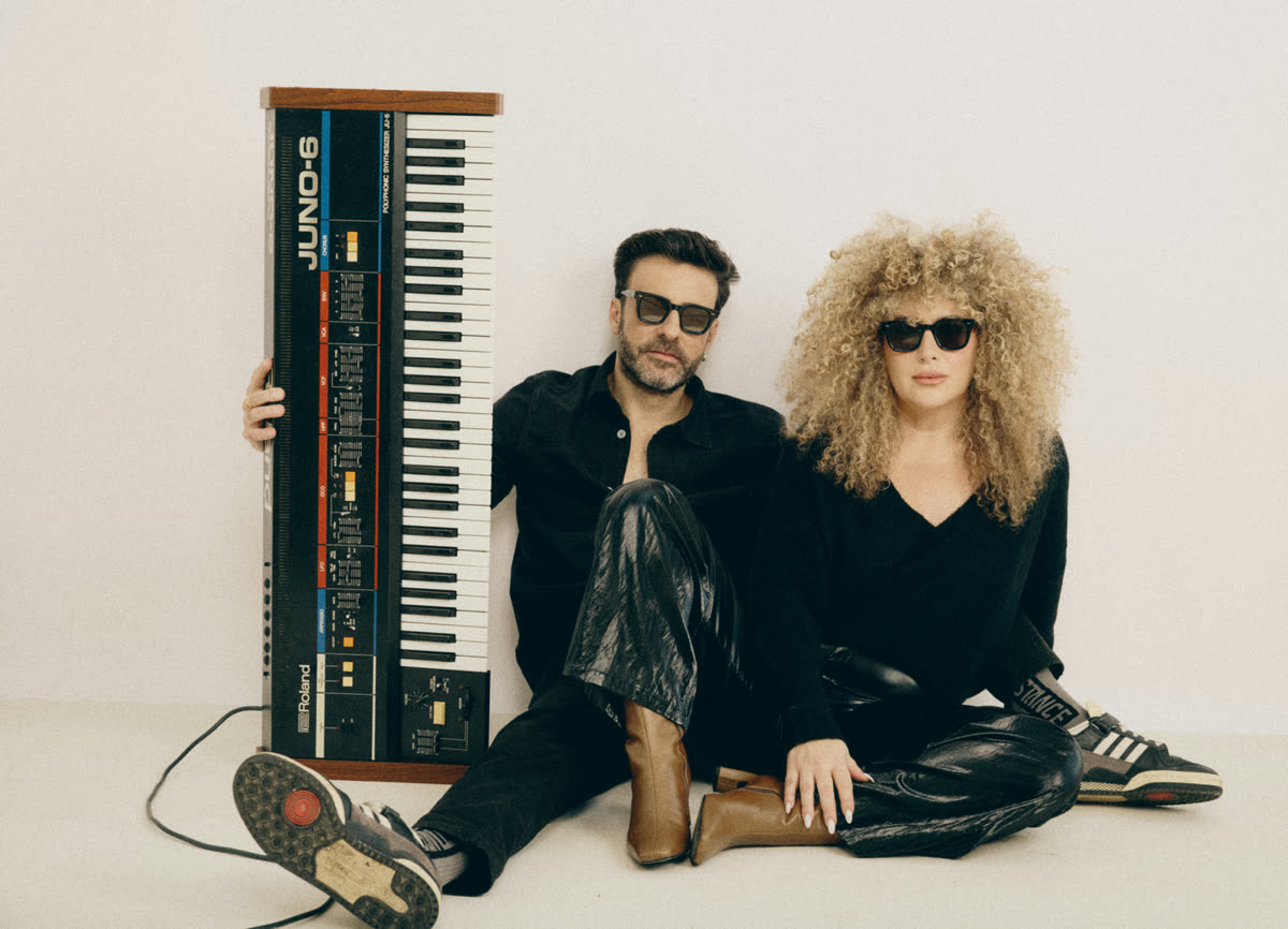 Niv and Meital, the founders of KNOB, sitting together with a vintage Roland Juno-6 synthesizer.